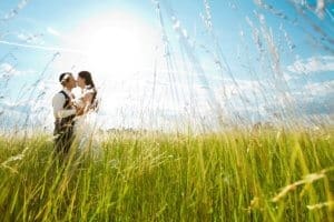 Beautiful bride and groom standing in grass and kissing. 