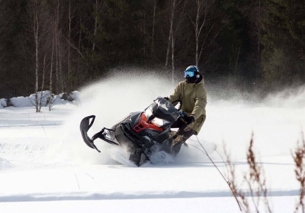 Athlete rides in the winter woods on a snowmobile.